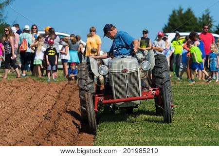 DUNDAS, PRINCE EDWARD ISLAND, CANADA - 25 Aug: Competitor plows with antique tractor while spectators look on at the PEI Plowing Match & Agricultural fair on August 25, 2017 in Dundas, PEI.