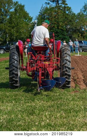 DUNDAS, PRINCE EDWARD ISLAND, CANADA - 25 Aug: Competitor plows with antique tractor while spectators look on at the PEI Plowing Match and Agricultural fair on August 25, 2017 in Dundas, PPEI.