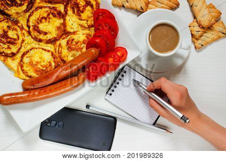 Breakfast of an omelette with sausages and coffee on a white wooden background
