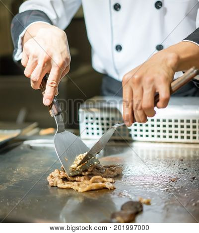 Hand Of Chef Cooking Beef Steak On Hot Pan In Front Of Customers.