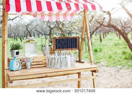 In The Park On The Green Lawn A Wooden Counter With A Lemonade. An Adorable Summer Lemonade Stand. C