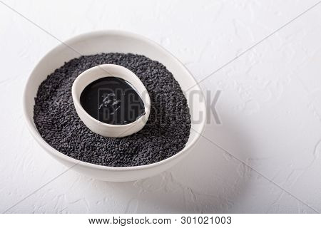 Black Tahini Sauce And Black Sesame Seeds In Bowls On White Background. Natural Paste Made From Sesa