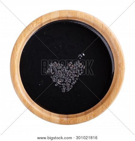 Black Tahini Sauce In Wooden Bowl Isolated On White Background. Natural Paste Made From Sesame Seeds