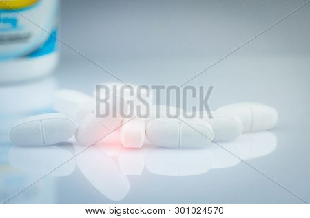 Calcium Tablets For Children Or Pregnant Woman. White Tablets Pills On Blurred Drug Bottle Backgroun
