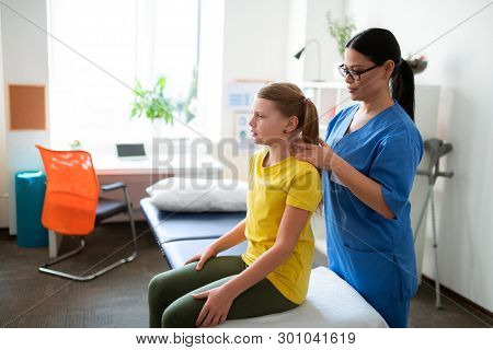 Concentrated Long-haired Nurse In Blue Uniform Processing Neck