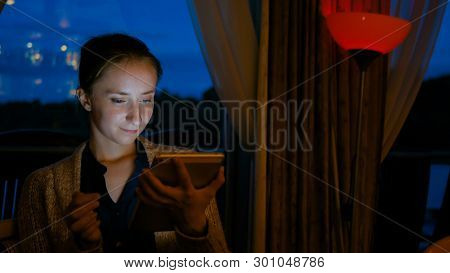 Woman Using Digital Tablet Computer Device In Cafe Of Cruise Ship. Evening Time, Lowlight. Technolog