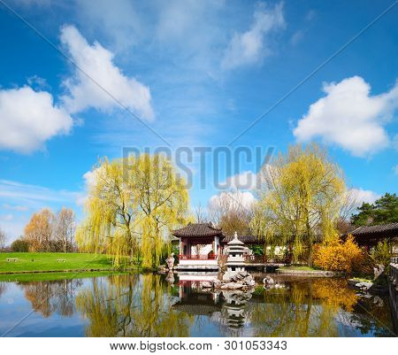 Stone Pagoda In The Pond Of A Formal Chinese Garden, Berlin, Germany. Focus On The Stone Tower In Th