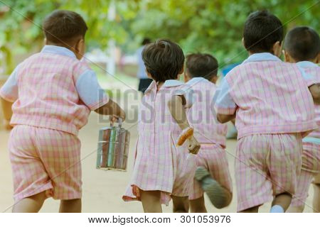 Back View Of Kindergarten Students Run Back To The Classroom After Having Lunch.