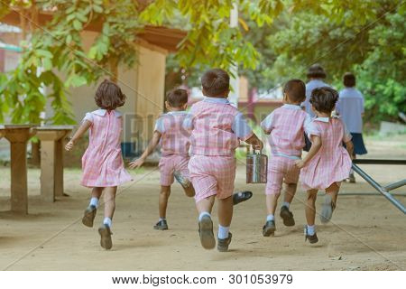 Back View Of Kindergarten Students Run Back To The Classroom After Having Lunch.