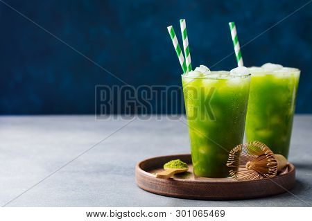 Matcha Ice Tea In Tall Glass On Wooden Plate. Blue Background. Copy Space