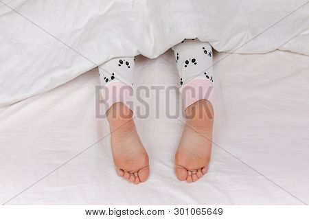 Pair Of Kid Bare Feet In Bed On White Sheets