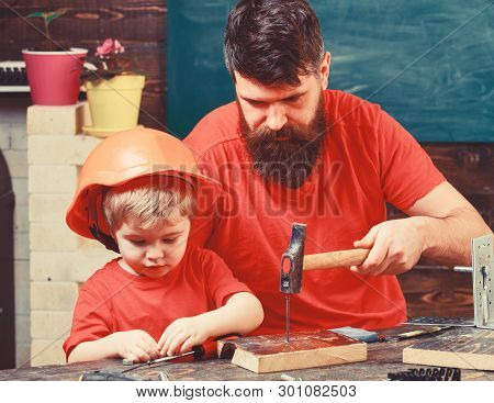 Boy, Child Busy In Protective Helmet Learning To Hammering Hobnails With Dad. Father, Parent With Be