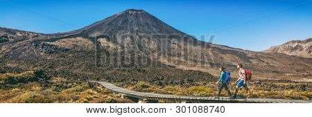 New Zealand Hiking Couple Backpackers Tramping At Tongariro National Park. Two hikers hiking by Mount Ngauruhoe. People living healthy active lifestyle outdoor panoramic banner.