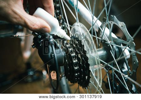 Closeup Of Male Hands Cleaning And Oiling A Bicycle Chain And Gear With Oil Spray. Working Process