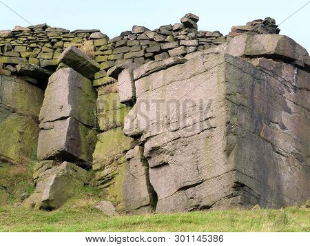 A Large Rock Outcrop Boulders With A Stone Wall Along The Top In Yorkshire Moorland