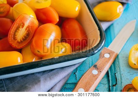 Small Cherry Tomatoes, Red And Yellow, In An Enameled Baking Sheet On A Blue Background