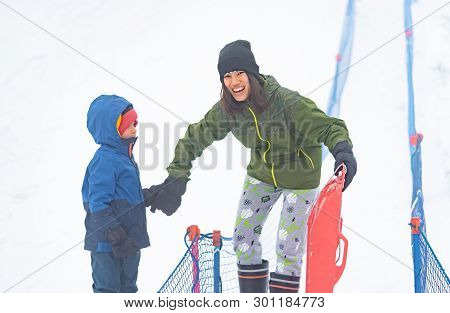 Mother Is Helping Her Boy To Ride The Sled