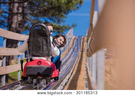 Excited young couple driving alpine coaster while enjoying beautiful sunny day in the nature