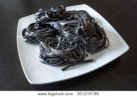 Dry Black Pasta With Cuttlefish Ink. Pasta Of Durum Wheat Semolina With Squid Ink On A Square Plate