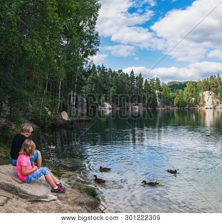 Adrspach, Czech Republic - August 16, 2018: Mother And Daughter Feeding Ducks On Lake In Rock City A