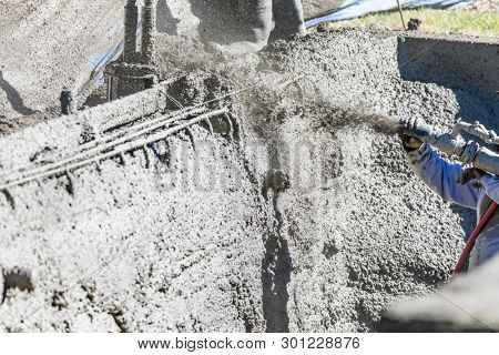 Pool Construction Worker Shooting Concrete, Shotcrete or Gunite Through Hose