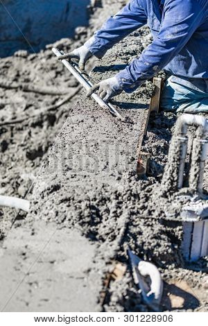 Pool Construction Worker Working With A Smoother Rod On Wet Concrete