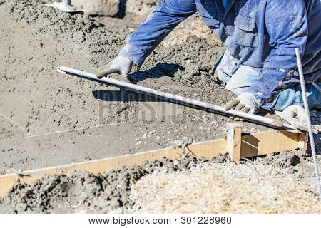 Pool Construction Worker Working With A Smoother Rod On Wet Concrete