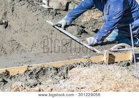 Pool Construction Worker Working With A Smoother Rod On Wet Concrete