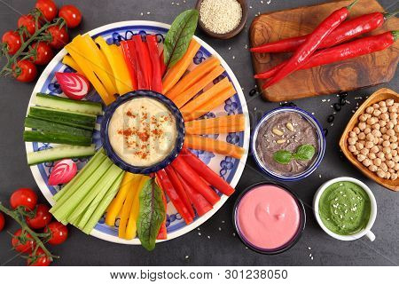 Colorful Fresh Vegetables Cut Into Strips On A Plate And Various Types Of Humus.