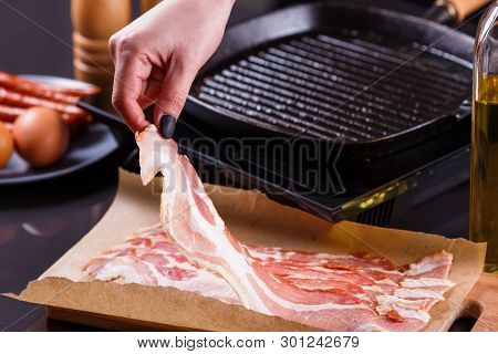 Young Woman In A Gray Apron Fries Bacon