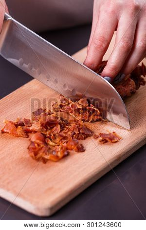 Young Woman In A Gray Apron Cuts Roasted Bacon