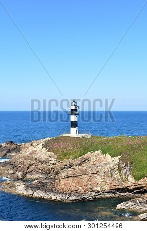 Lighthouse At Isla Pancha. Island With Cliff And Violet Flowers, Ribadeo, Spain, Sunny Day.