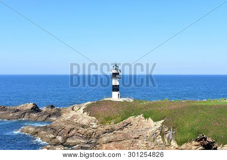 Lighthouse At Isla Pancha. Island With Cliff And Violet Flowers, Ribadeo, Spain, Sunny Day.