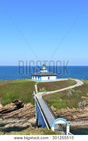 Lighthouse At Isla Pancha. Island With Cliff And Violet Flowers, Ribadeo, Spain, Sunny Day.
