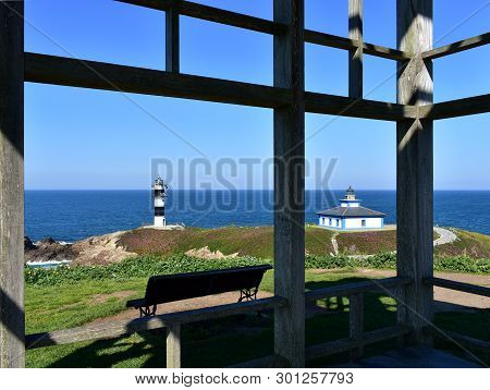 Island With Two Lighthouses From A Viewpoint With Grass, Hut And Bench. Isla Pancha, Ribadeo, Spain,