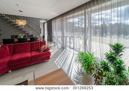 Dining Area And Living Room In The Interior Of Modern House. Cozy Home Interior With Red Sofa, Dinin