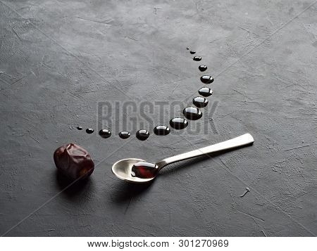 Black Ramadan Background With Dates And Dates Syrup Poured In The Shape Of Crescent Moon.