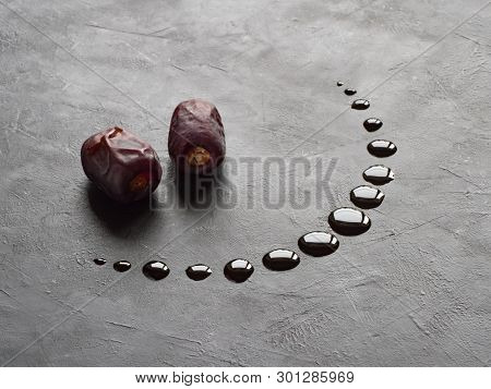 Black Ramadan Background With Dates And Dates Syrup Poured In The Shape Of Crescent Moon.