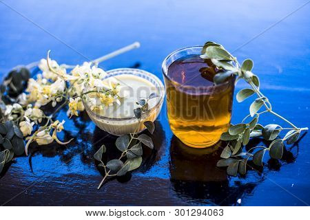 Bunch Of Flowers Of Drumstick On Wooden Surface Along With Its Extracted Water Or Tincture In A Glas