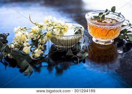Bunch Of Flowers Of Drumstick On Wooden Surface Along With Its Extracted Tea And Paste Of Flowers In