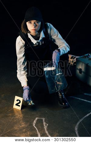 Serious Investigator Holding Dollar Banknote And Ziploc Bag At Crime Scene