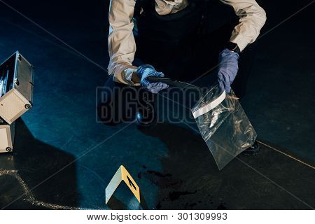 Cropped View Of Investigator Putting Knife In Ziploc Bag At Crime Scene