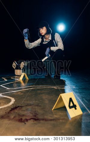 Investigator Holding Knife And Ziploc Bag At Crime Scene