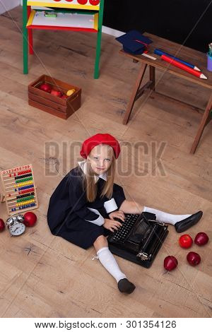 Back To School! The Girl In The Beret Sits With A Typewriter And Learns In Class. On The Blackboard 