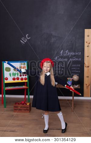 Back To School! A Little Girl Stands With Large Pencils In Her Hands At School.  The Kid Is Studying