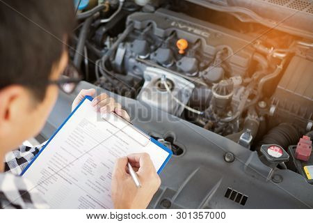 The Car Mechanic Working In The Car Garage Is Checking The Engine.
