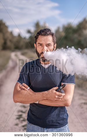 Confident Vaper Enjoying Electronic Cigarette Outside. Man Really Likes Process Of Smoking.
