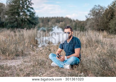 Brutal Man Smoke Electronic Cigarette And Exhals Smoke Cloud. Vaping Concept.