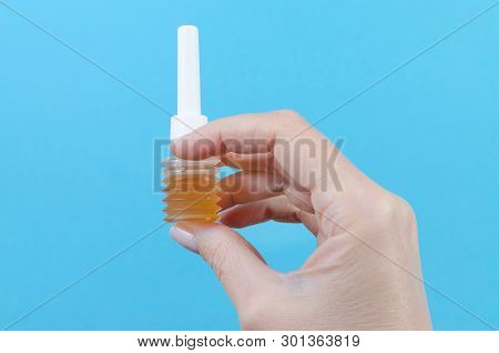 Womans Hand With Mini Enema On Blue Background