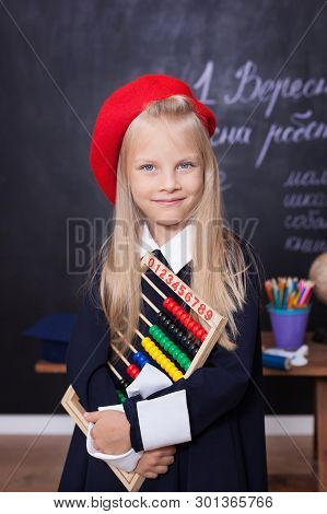 Back To School! Cheerful Little Girl Stands With Bills. School Concept. Schoolgirl Answers At Lesson